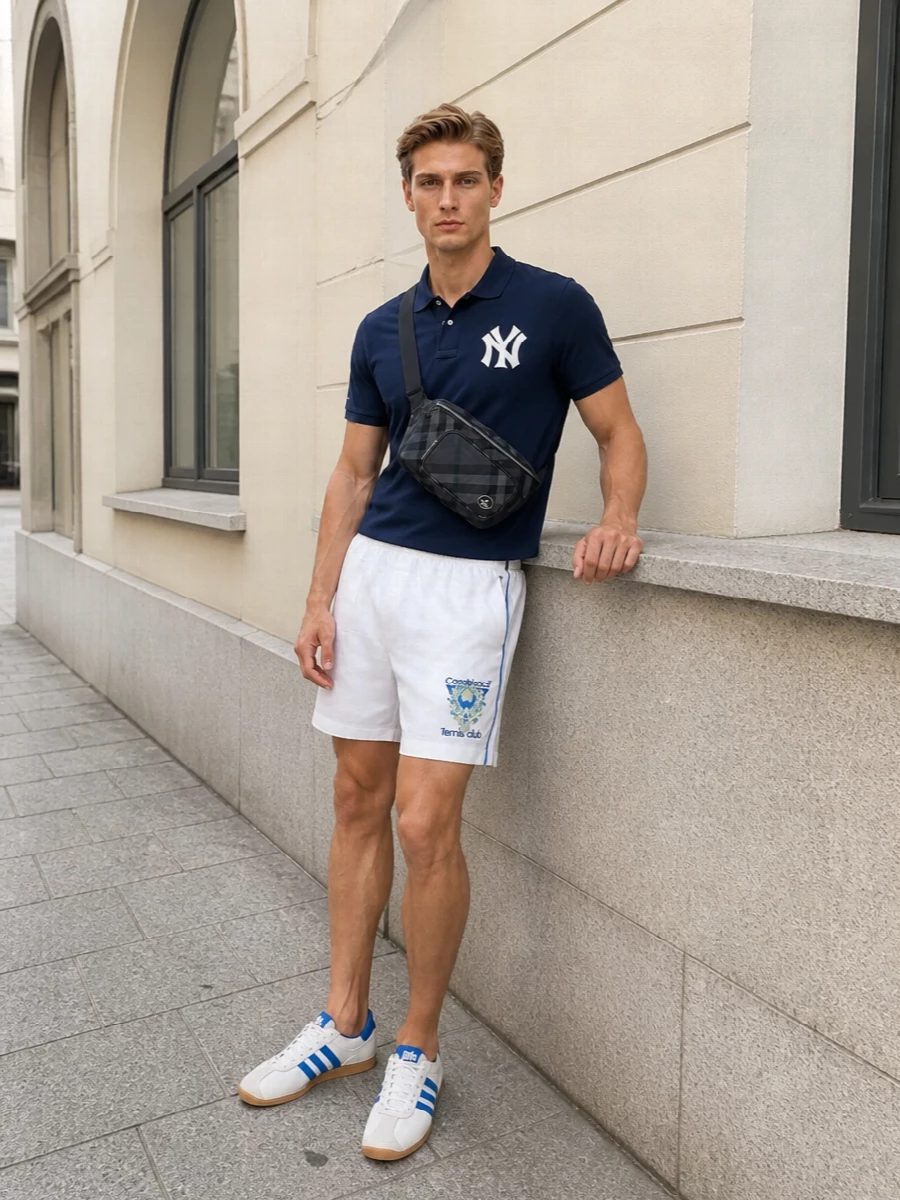 Preppy sport goes properly luxe here, with the varsity-style navy polo grounded by crisp white tennis shorts that nod to classic country club kit. Cobalt-striped court sneakers keep everything feeling agile and young, while the compact crossbody adds just enough structure for city days and summer travel. The result is polished athletic energy you can wear from brunch to a late match at the park.