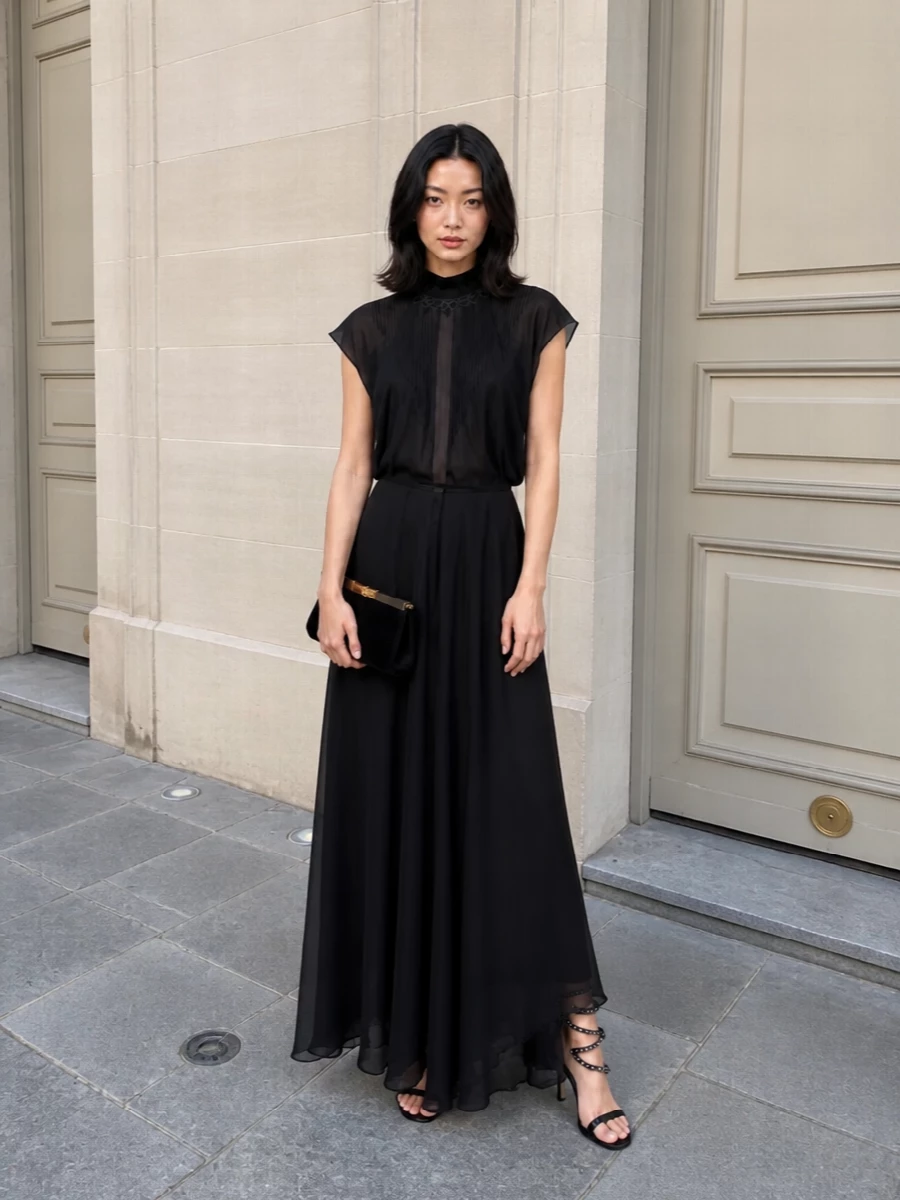 A study in shadow and light, this pairing lets the Fendi column gown stay fluid and minimal while the crystal spiral sandal draws the eye in motion around the hem. The velvet clutch echoes the gown’s depth, its subtle gold hardware offering just enough warmth to keep the whole ensemble rich rather than stark. It is black tie dressing for someone who prefers nuance over noise.