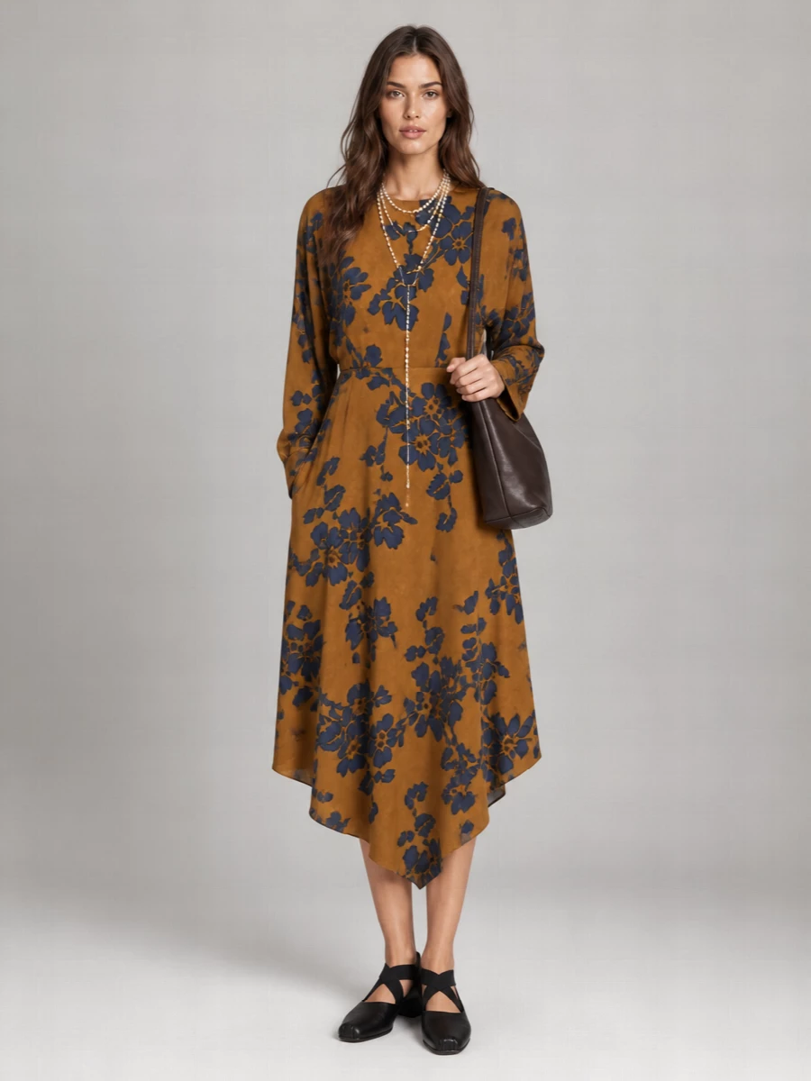 Ochre florals and inky blue set a quietly dramatic base, with sculptural black flats and a deep chocolate bucket bag keeping the mood grounded and lived in. A draped pearl lariat and softly painterly scarf add romance and texture, so the whole outfit feels bohemian, art-minded and ready to move from daytime wandering to low-lit dinners. The silhouette stays fluid and asymmetric, letting the dress lead while the accessories whisper around it.