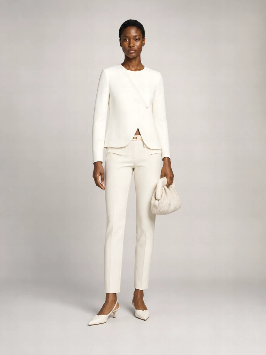 An ivory-on-ivory palette keeps the focus on line and cut, from the high-waisted tailored trouser to the asymmetric blazer. The slingback kitten heel and sculptural clutch add just enough formality and texture for client meetings or dinner reservations without breaking the quiet mood. A slim tonal belt quietly sharpens the waist so the proportions stay long and lean.