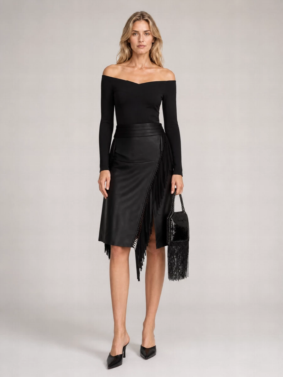 An all-black Stella McCartney evening ensemble that leans into clean architecture against fluid fringe. The sculpted off-shoulder top and high-waist asymmetric skirt create a long, confident line, while pointed mules and a fringe-detailed mini bag keep the mood sharply night-focused yet minimal.