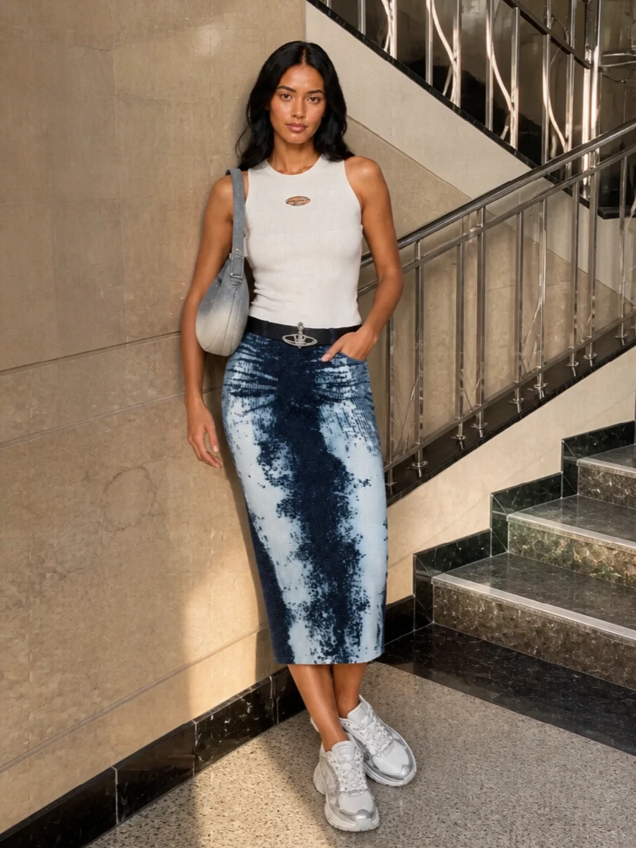 This is a fresh Y2K-skewed city outfit built around the inky tie-dye midi skirt, grounded with a clean off white knit tank to keep the graphic pattern in focus. Chunky white and silver runners drop it into a relaxed, all-day streetwear register, while the ombré denim shoulder bag and navy belt quietly echo the palette and hardware for a tight, considered finish. It feels confident and graphic, but still easy enough to wear from daytime roaming to low-key nights out by just switching up jewelry and makeup.