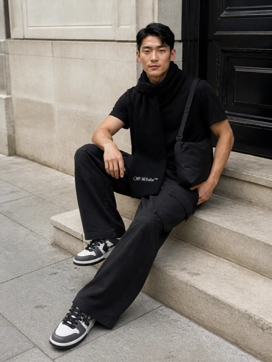 This look builds a pure Rick-inspired column: the elongated black tee drops cleanly into high-rise, soft-black wide-leg cargos for a stark, architectural silhouette. Monochrome Off-White courts and a padded Balenciaga shoulder bag keep the mood urban and intentional, while the ribbed black scarf adds winter function and a quiet logo note without breaking the minimalism.