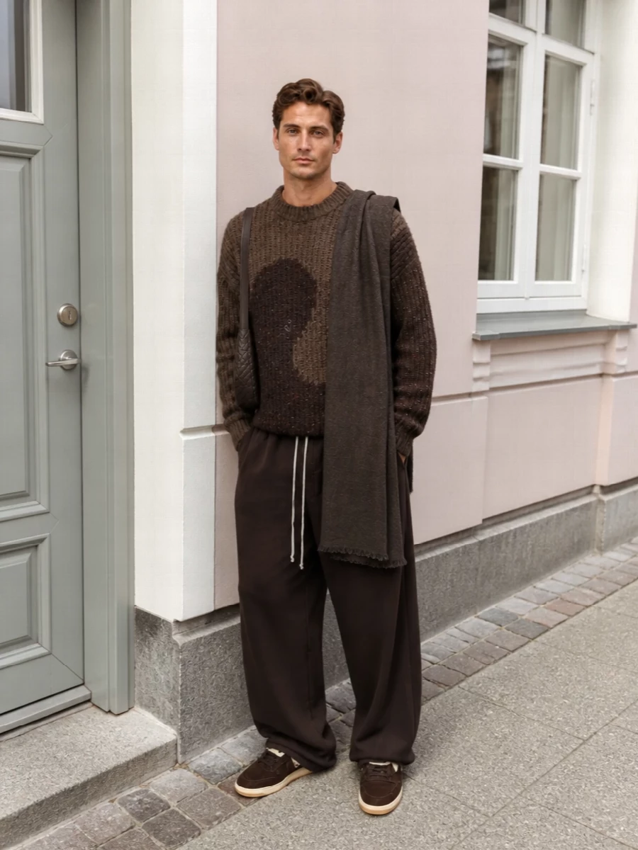 Earthy browns carry through from the graphic ribbed knit into the ultra-wide DRKSHDW trouser, keeping the proportions relaxed and fluid. Dark chocolate shearling sneakers and a slim Bottega crossbody add tactility without breaking the minimalist streetwear line. The Rick scarf ties the shadowy tones together for a quiet, graphic winter uniform.