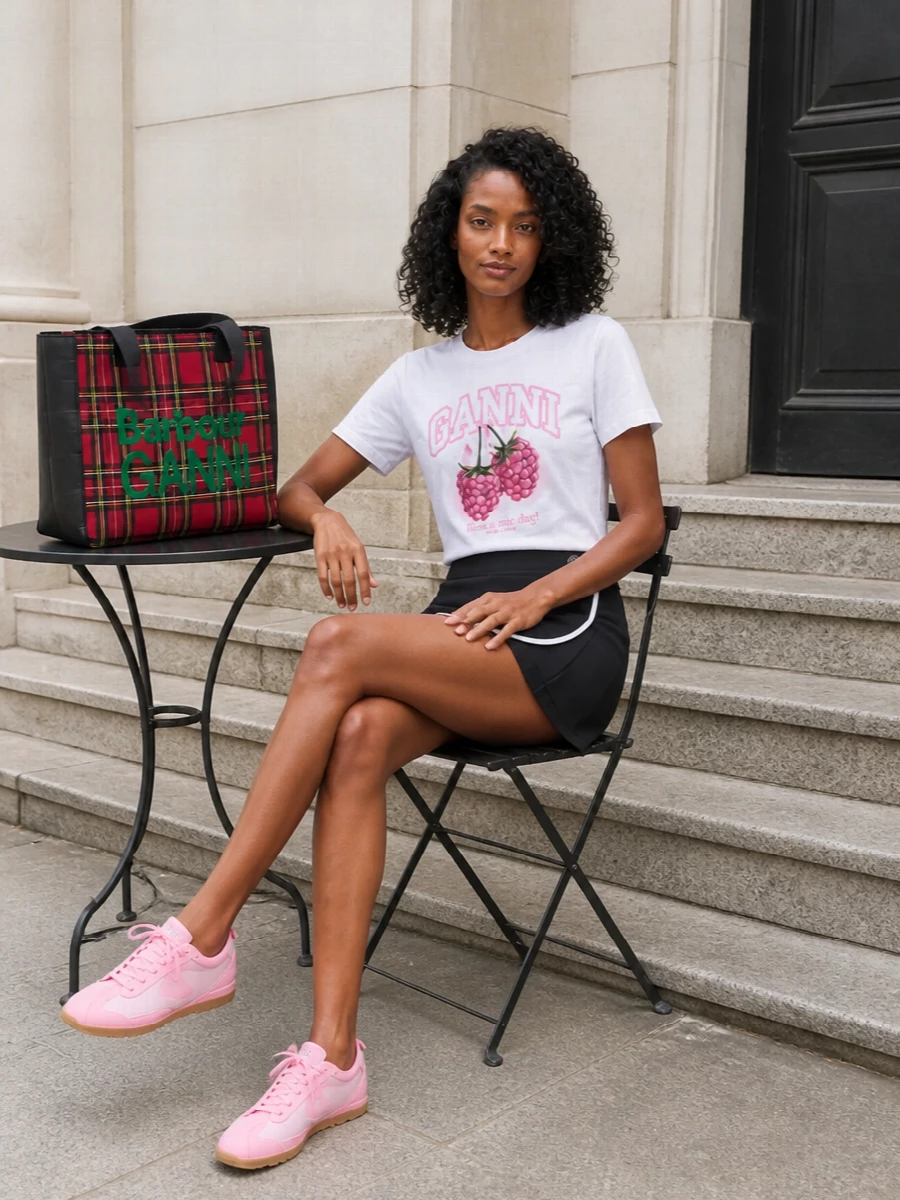 A graphic Ganni tee pairs with a sporty Ambush wrap mini for a mix of preppy stripes and streetwear edge. Bubblegum-pink Jacquemus sneakers pull out the berry tones, while the Barbour tartan tote adds a playful, city-ready pop. The result is a light, optimistic outfit that feels perfect for weekend wandering and coffee runs with friends.
