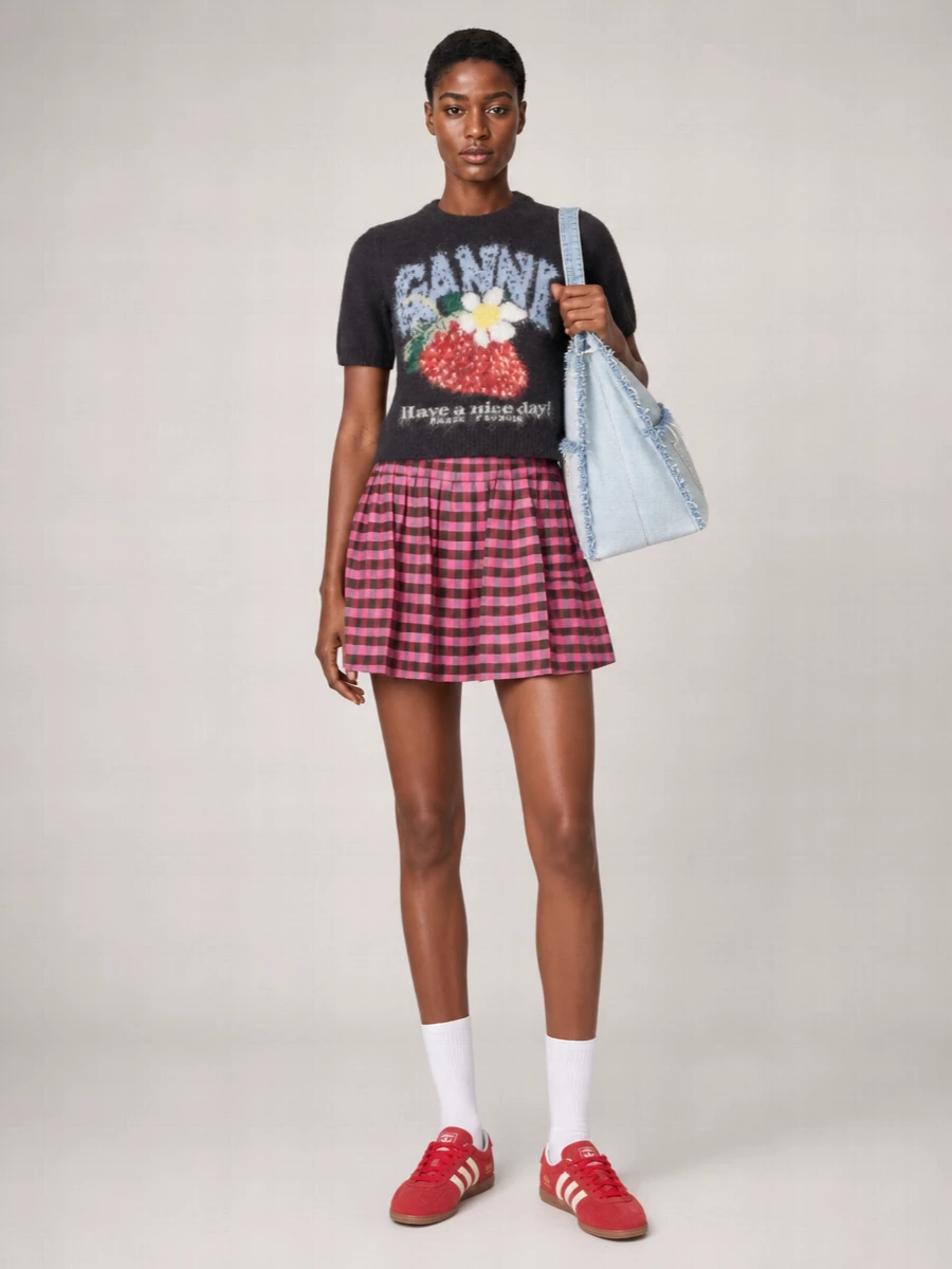 Ganni’s fuzzy graphic knit meets a Kenzo gingham mini for a campus-ready mashup of prep and y2k, all in punchy charcoal, pink and red. Adidas Gazelles and Alexander Wang’s blown-up denim tote keep it grounded in streetwear, so it feels as easy for coffee runs as it does for gallery afternoons. The proportions stay flirty and light, with every accessory echoing the playful color story rather than overpowering it.