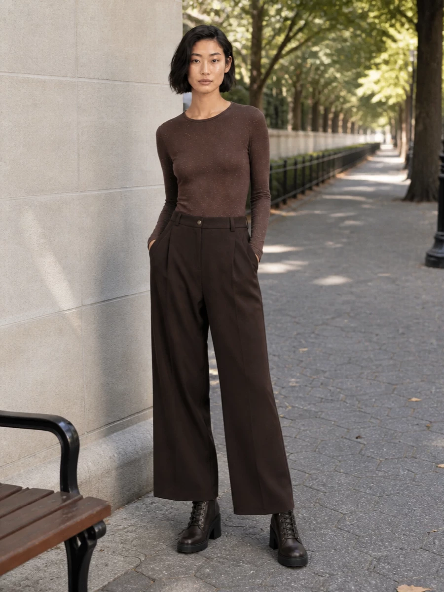 A deep chocolate column of fine knit and wide-leg tailoring lets the lace‑up boots feel intentional rather than aggressive. The tonal brown story, lifted by subtle sparkle and refined hardware, keeps the outfit city ready and quietly confident for day to dinner. It is an easy way to do head-to-toe depth without defaulting to black, while the proportions stay long and clean around the chunky heel.