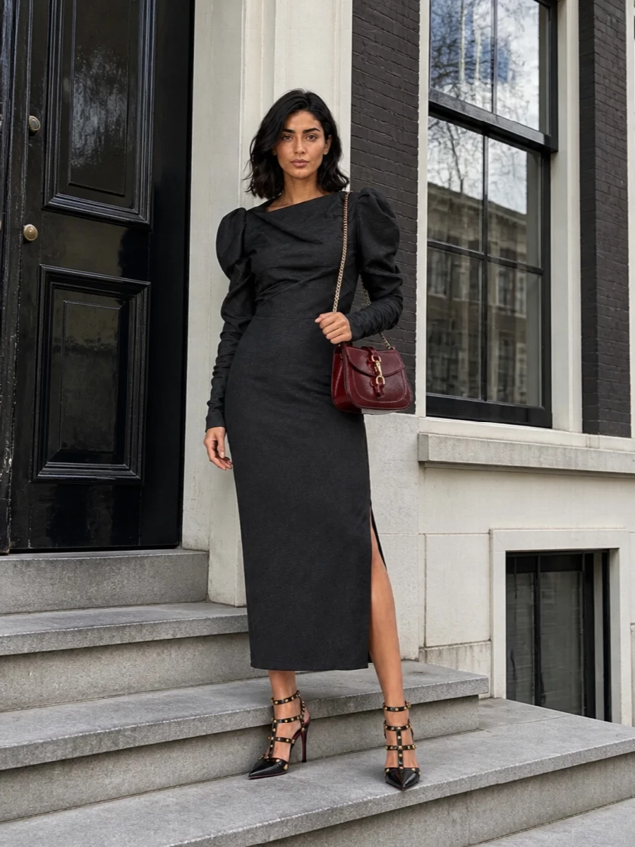 The Vivienne Westwood charcoal midi sets a sculpted, almost architectural base that amplifies the sharp attitude of the black Valentino Rockstud heels. A glossy burgundy Gucci shoulder bag threads in just enough color and gold hardware to pick up the studs and the shoe’s red lining, keeping the whole ensemble firmly in that romantic, high-tailored evening space. Choosing the dress route here keeps the silhouette clean and commanding, letting the footwear and structure do the talking rather than breaking the line with separate top and bottom.