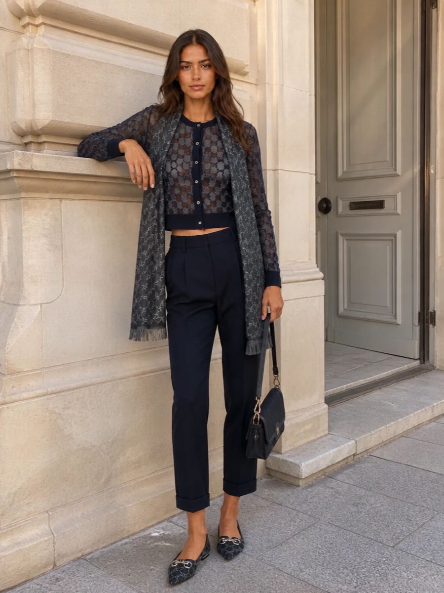 A deep navy narrative keeps this ensemble calm and precise, with the sheer GG knit sitting cleanly over sharply cut tapered trousers. Pointed GG flats and a structured shoulder bag keep the logo language consistent yet quiet, while a slate-toned scarf adds just enough softness to the tailored lines. It is polished, preppy and quietly assured, ideal for days that move from desk to discreet dinner.