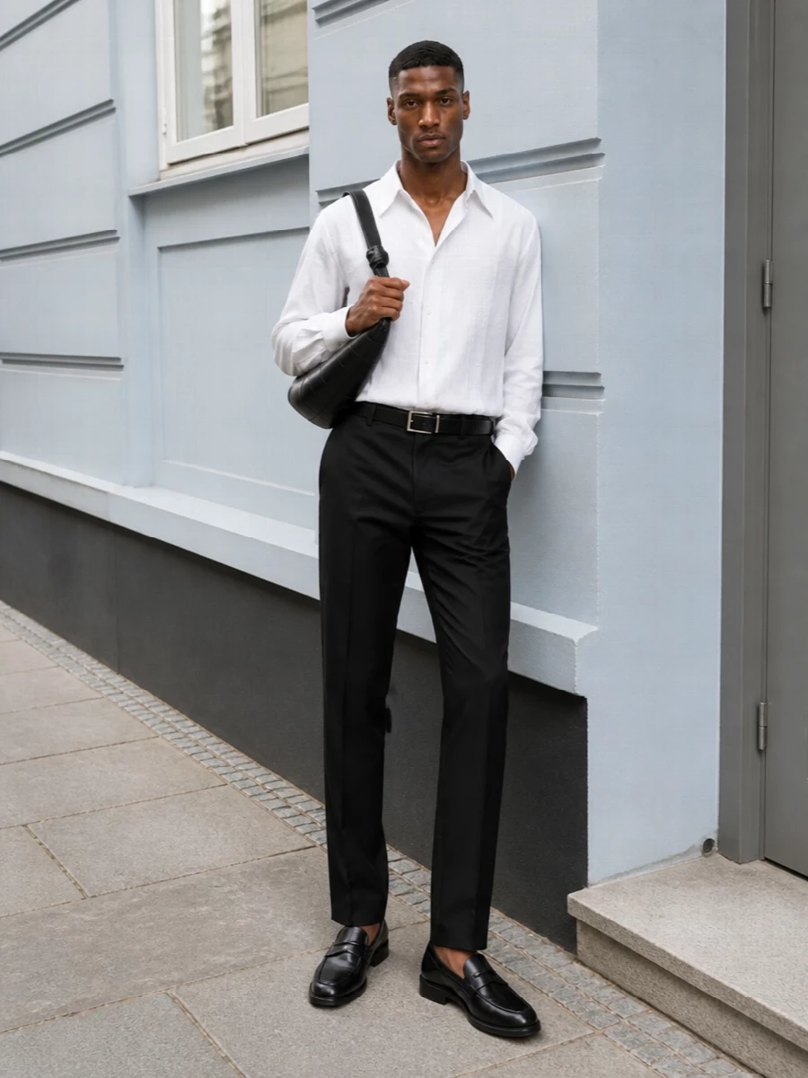 Soft tux shirting and sharply cut black tailoring create a quietly dressed-up uniform that reads precise rather than precious. The straight trouser, penny loafer and slim black belt keep the proportions clean and vertical, while the curved leather shoulder bag adds just enough texture to feel considered for long city days that can slide into dinner.