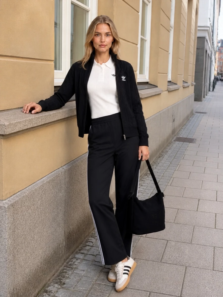 I’m building around the track-knit energy of the Adidas outerwear, so I stay in the top-and-bottom route instead of a dress, keeping the story purely sport-street. The ribbed white polo and black striped track pants create a clean monochrome column under the jacket, while retro trainers and a stealthy Y‑3 bag keep it polished enough for all-day city movement. The result is graphic, comfortable and intentionally branded without feeling shouty.