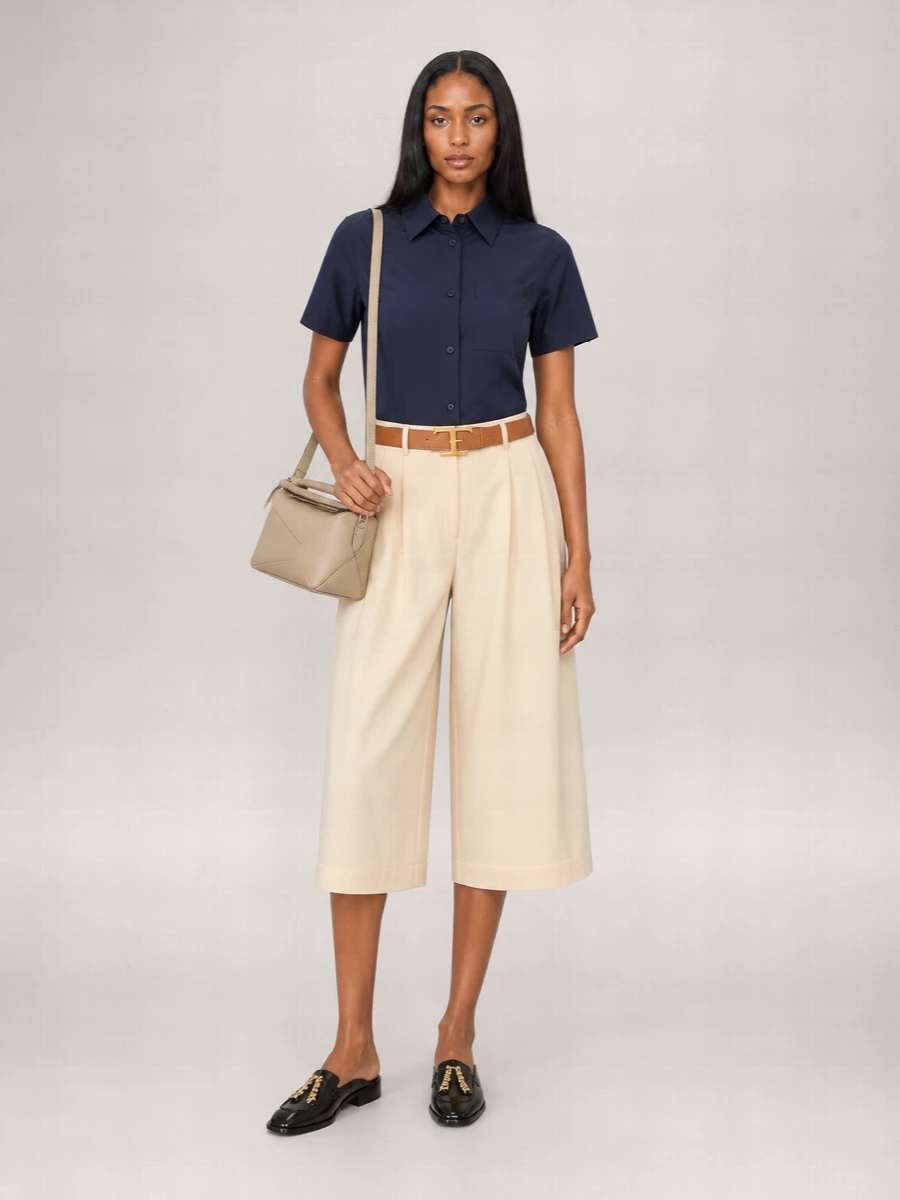 Deep navy meets soft beige for a pared-back palette that feels calm and precise. The cropped wide-leg proportion keeps the shirt from reading corporate, while the backless loafer and structured tote keep everything city ready yet relaxed. A tan belt adds just enough definition and warmth to finish the silhouette with intention.