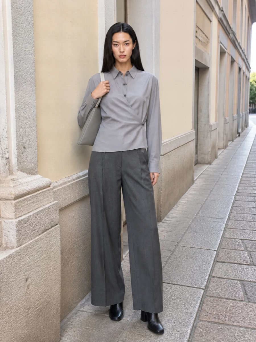 Cool grey and charcoal sit together in a precise, elongated silhouette that feels considered from every angle. The asymmetric shirt and high-rise wide leg create a clean vertical line, sharpened by black leather and a structured shoulder bag in soft dove grey. It is quiet, modern tailoring for days that move fluidly from office to evening without a change of clothes.