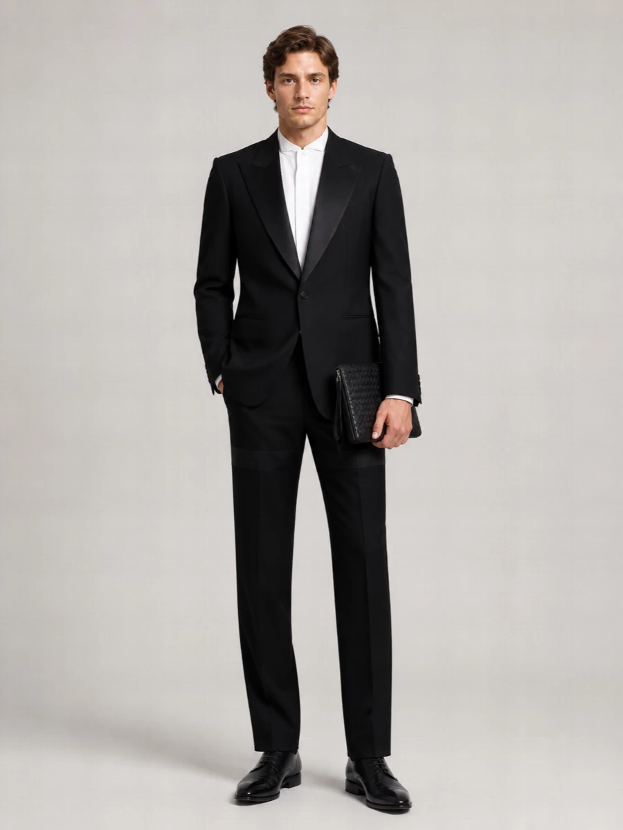 This is a modern black-tie ensemble that shifts Gucci’s relaxed tux sensibility into a sharper, slimmer line while keeping the same quiet authority. The Ferragamo-inspired trouser and Louboutin oxford create a clean, elongated silhouette, and the woven Bottega clutch adds just enough texture to keep the all-black palette rich rather than flat. It is built for formal dinners and ceremonies where the details matter but the attitude stays calm and assured.