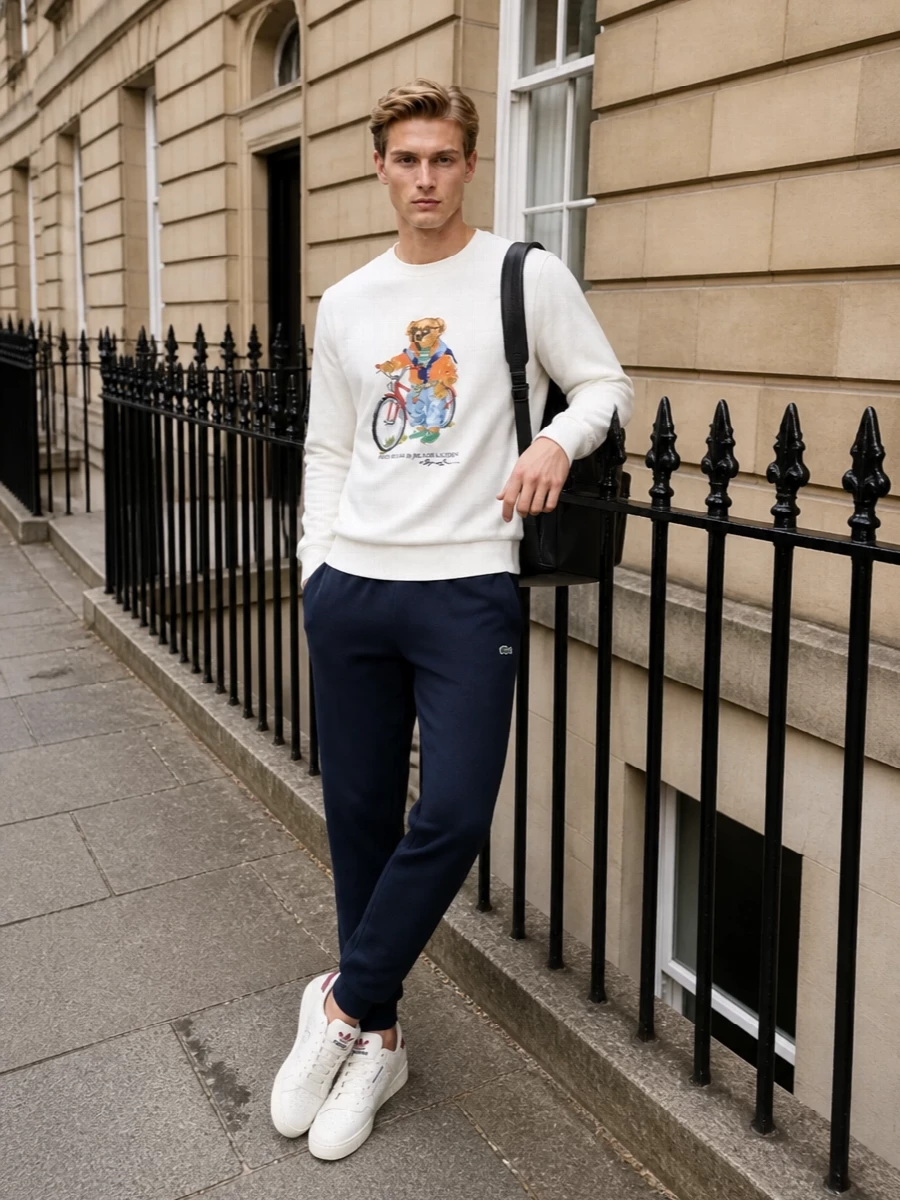 The Polo Bear sweatshirt stays center stage against clean navy joggers and cream court sneakers, creating a polished yet easy mix of sport and preppy. The restrained palette lets the graphic do the talking, while the streamlined backpack keeps the whole outfit practical and city ready. It is relaxed enough for weekends yet put together enough for casual meetups or travel days.