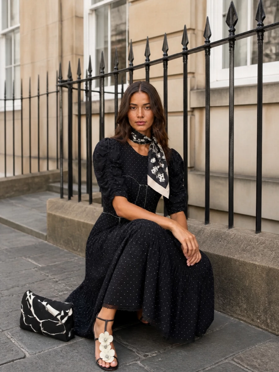 A romantic black-and-ivory story that feels made for summer cocktails and gallery openings. The stiletto sandals and graphic mini bag sharpen the soft polka-dot dress, while the floral scarf adds a final, whispery layer of femininity. It is polished without feeling strict, dreamy without losing definition.