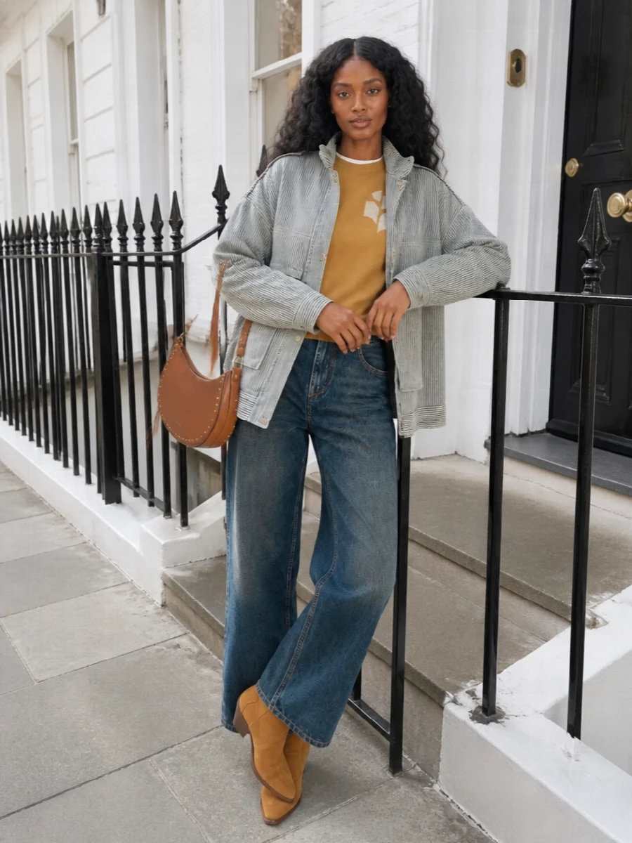 This outfit leans into the coat’s utilitarian stripes by pairing it with a slouchy camel sweatshirt and wide indigo denim for a relaxed, Parisian-off-duty feel. Tan western boots and a cognac saddle bag reinforce the warm, boho accents, grounding the cool-toned outerwear in a cohesive autumn palette. I chose the top-and-jean route over a jumpsuit or dress so the coat remains the anchor, with easy layers you can strip back as the day shifts.