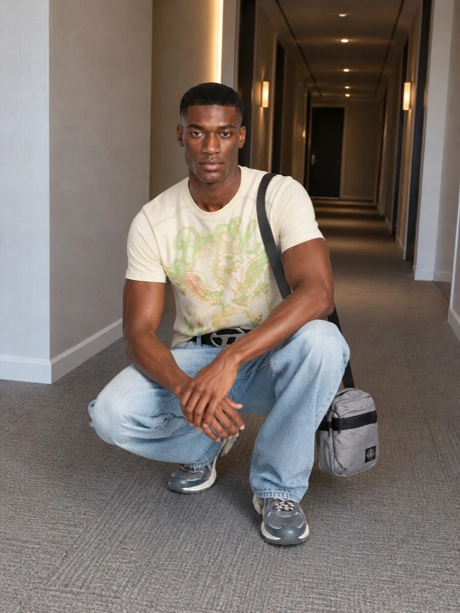 A washed griffin tee and loose light-wash denim set a sun-faded Y2K street base, all soft cream, lime and blue. Technical grey runners and a compact grey crossbody pull in a subtle sport edge, while the bold Diesel belt punctuates the waist with early-2000s attitude. The result is relaxed but graphic, built for all-day city wear with a clear brand story.