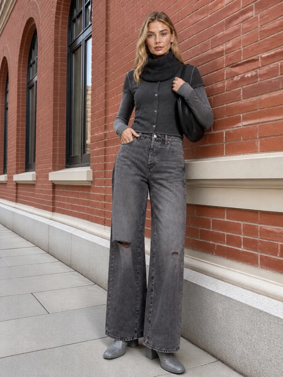 Charcoal and washed grey tones stack into a clean, urban uniform built around subtle texture and quiet detail. The close-cut knit against high-rise wide denim creates a long, easy line, while sculptural boots and a curved black shoulder bag finish it with low-key precision. It is the kind of monochrome streetwear that feels considered without ever tipping into fuss.