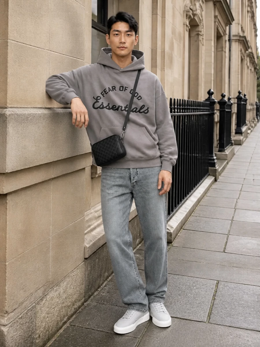 Taupe logo fleece, washed grey denim and pale grey sneakers create a calm, tonal street uniform that feels relaxed but intentional. The straight leg keeps the volume balanced under the slouchy hoodie, while the compact black crossbody adds a subtle, city-ready edge. It is an easy off-duty combination that reads modern and quietly confident from head to toe.