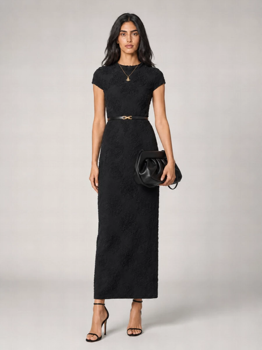 A sculpted black maxi is paired with barely-there stilettos and a structured pleated clutch for a clean, monochrome evening ensemble. A single orb pendant and a refined slim belt introduce just enough shimmer and definition to keep the silhouette sharp yet romantic.