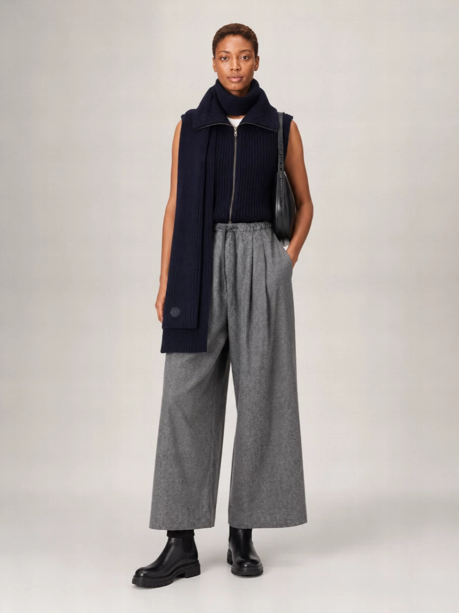 Ink navy and soft grey sit quietly together here, all about proportion and texture rather than contrast. The high-waisted wide leg creates a long, relaxed line under the structured zip vest, while black leather boots and a curved shoulder bag keep the palette sharp and city ready. It is an easy, understated uniform for cooler days when you want to feel wrapped without looking bulky.