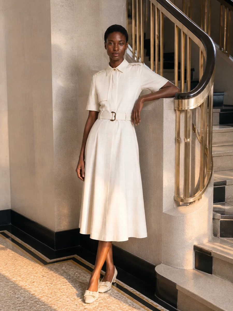 The Burberry ivory shirt dress and cream Valentino pumps create a quietly authoritative city outfit that feels soft yet precise. The camel Dolce&Gabbana top‑handle bag slots in naturally, its structured shape and warm leather echoing the dress’s belt and buttons. Choosing the dress route over separates keeps the silhouette clean and columnar, letting the textures and gold hardware do the talking without visual clutter.