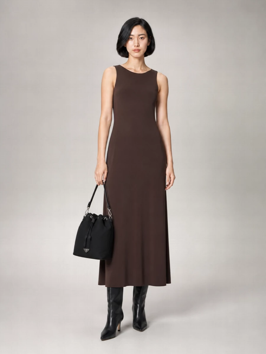 I’m building this around the Max Mara chocolate column dress rather than separates, because its long, minimalist line best echoes the Prada bag’s refined ease. The dark dress and black bucket read as one quietly graphic column, with the sleek knee-high boots adding just enough structure without interrupting the flow. It is a calm, grown-up city outfit that moves easily from late afternoon into dinner all year.