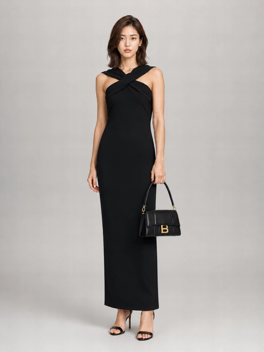 A sculpted black column dress and patent stiletto sandals create a long, uninterrupted line that feels confident and pared back for evening. The silhouette is all about clean architecture at the neckline and hem, letting the subtle sheen and bare shoulders carry the drama. A structured black baguette keeps everything polished and minimal, adding just enough hardware to catch the light without crowding the outfit.