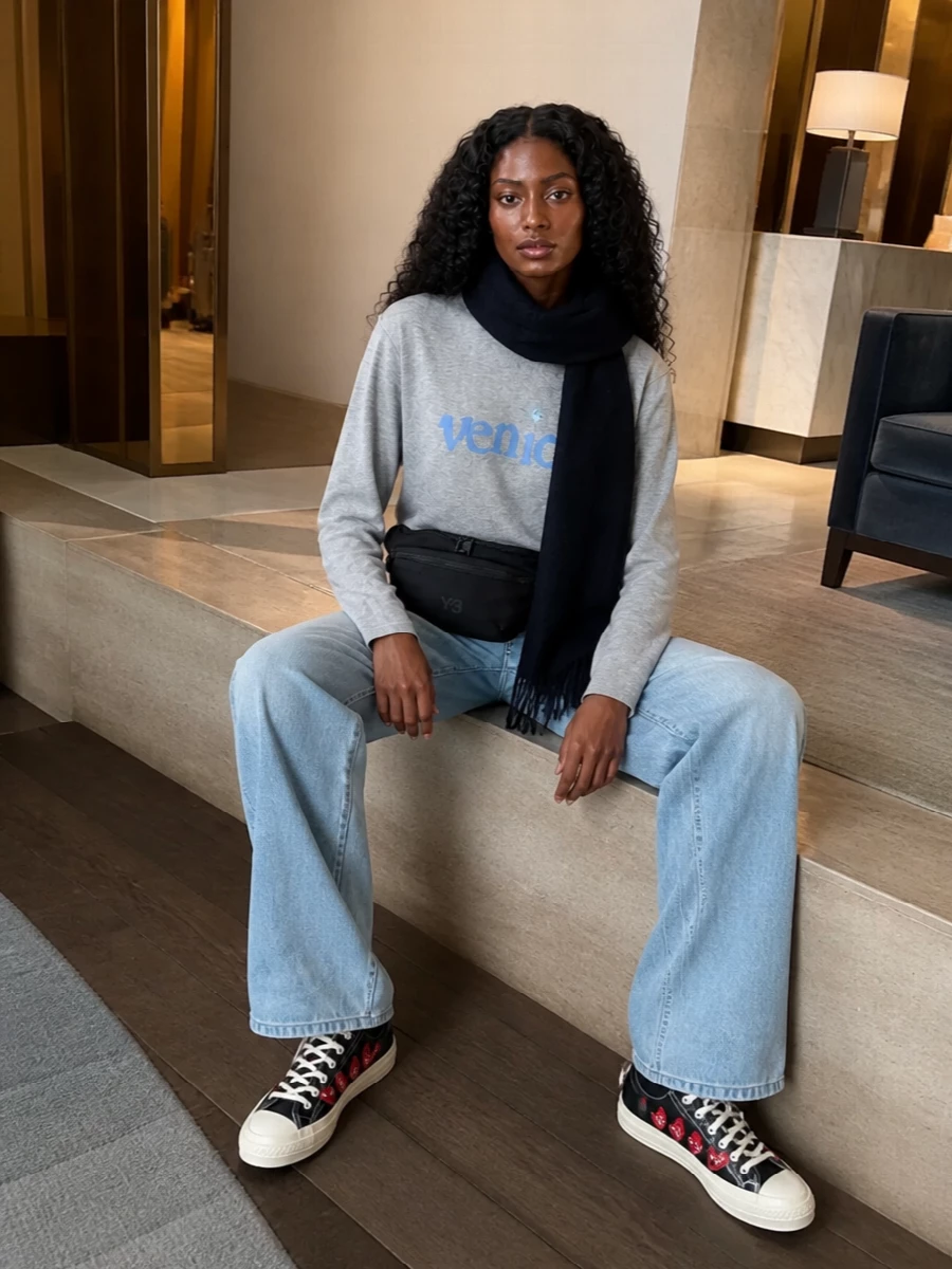 Erl’s Venice sweatshirt, light denim and the Comme des Garçons Play sneakers lean into an easy West Coast street story with a subtle graphic twist. The Y-3 belt bag and navy Ganni scarf keep everything hands free, warm and city ready without adding bulk or noise. It is an off duty uniform for cold days that still feels thought through from palette to proportion.