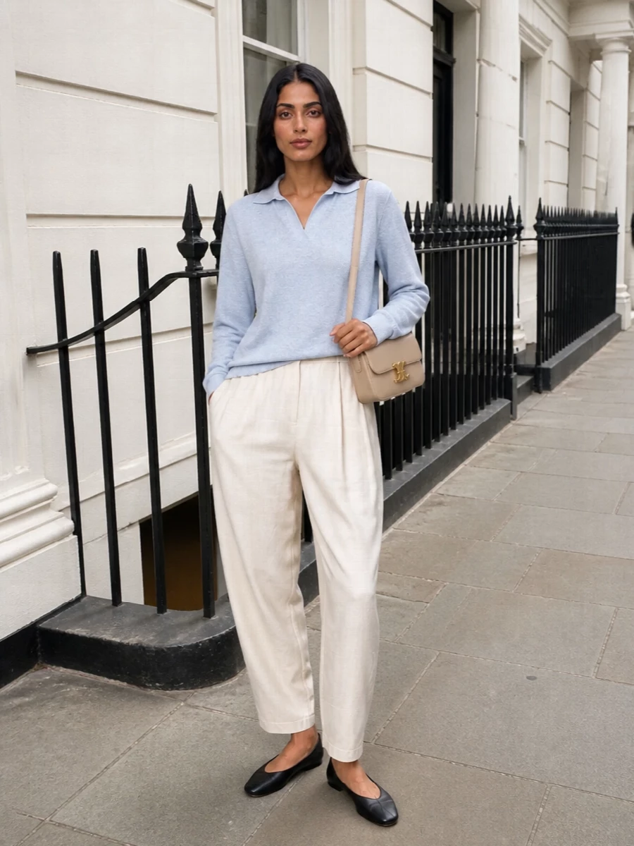 Soft ivory pleated trousers anchor the look, paired with the pale sky-blue collared knit for an easy, quietly refined take on menswear shirting. Black ballerina flats keep the silhouette clean and grounded, while the structured beige Celine shoulder bag introduces a compact, polished contrast that still sits comfortably within the neutral, minimalist palette. The result is a serene SS uniform that feels tailored yet completely unforced.