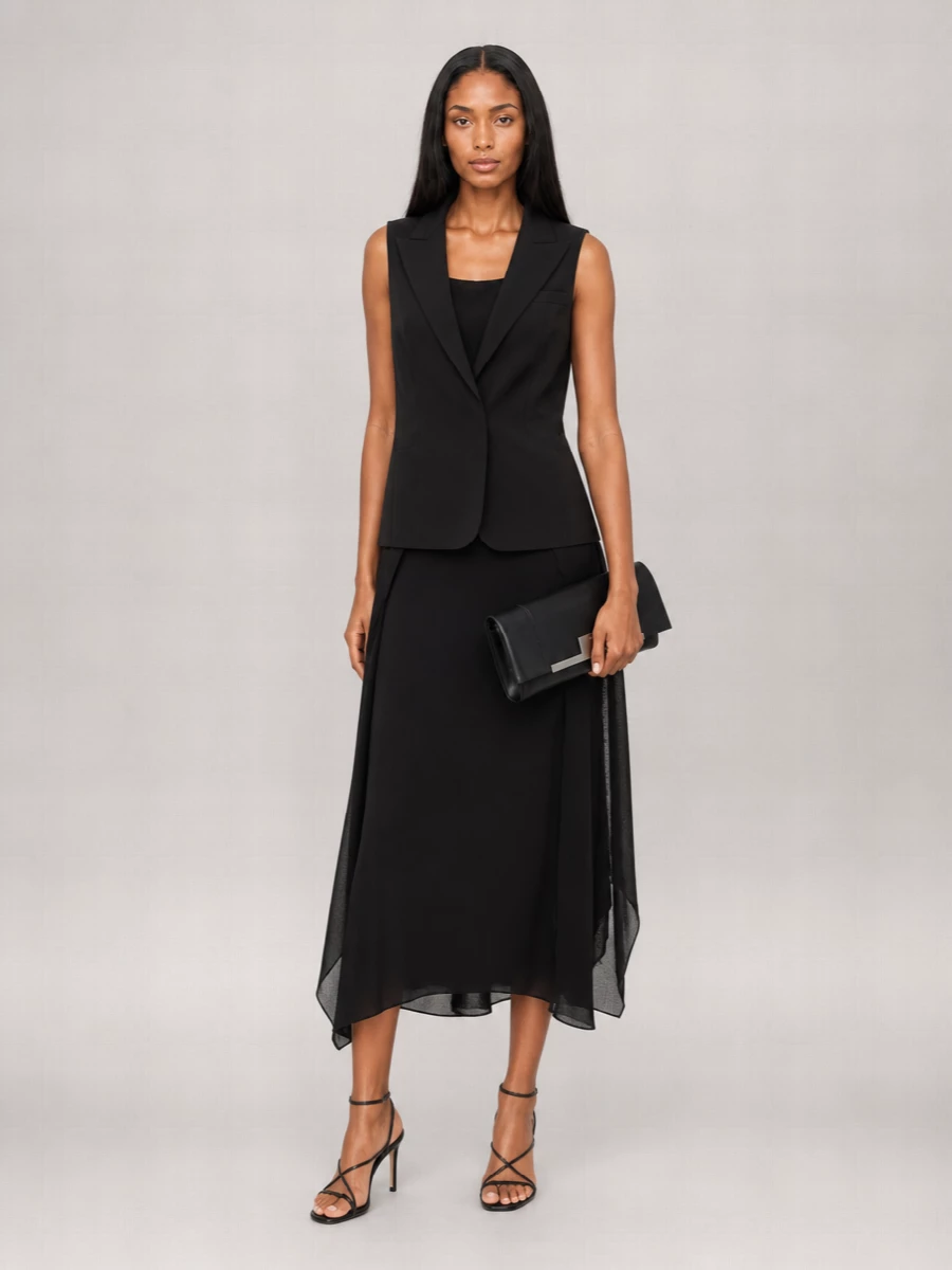 A liquid black column dress is kept rigorously monochrome, paired with fine black strappy heels that feel like jewellery rather than ornament. A sharp fold-over clutch in smooth black leather completes the quietly precise, gallery-dinner mood without breaking the serene line.