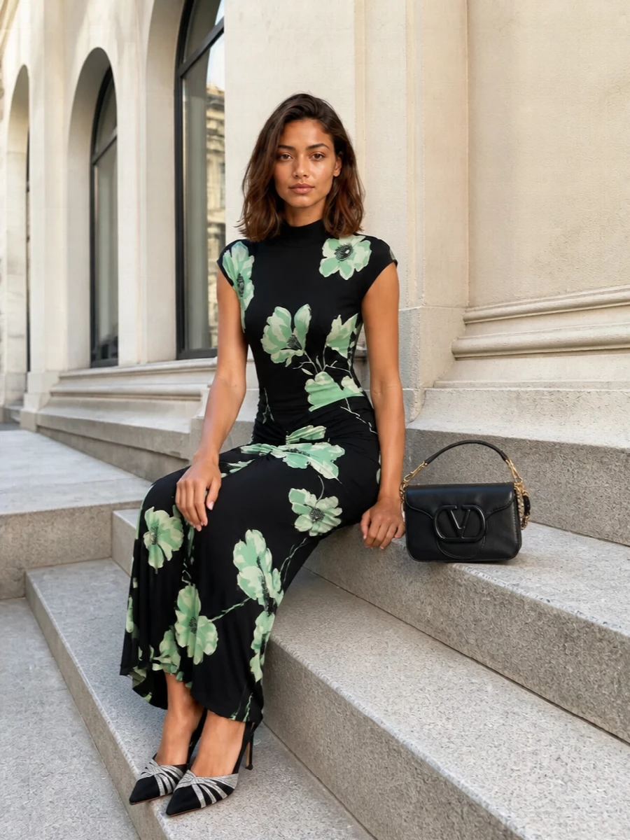 Alaïa’s inky floral column meets sharp black crystal slingbacks and a sculpted Valentino shoulder bag for a quietly opulent evening ensemble. The palette stays restrained in black, mint and gleaming metal, so the ruching, cut and movement of the dress stay in focus while the accessories simply sharpen the silhouette.