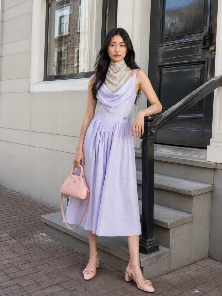 Romantic pinstripes meet soft blush accessories for a summer-ready city ensemble that feels sculpted yet airy. The corseted waist and draped neckline stay in focus, framed by low, modern block heels and a petite top-handle for a polished, slightly subversive party finish. The gauzy floral scarf picks up the dress’s gentle movement, adding a washed, painterly layer of colour at the neck or shoulders.