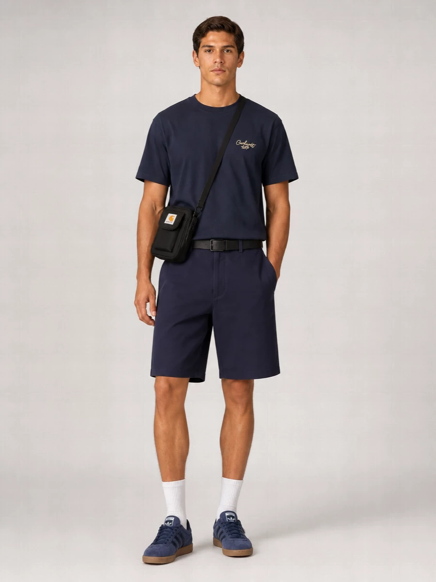 Navy Carhartt shorts and the boxy tee create a calm, monochrome base that feels relaxed but considered. Terrace-inspired gum-sole sneakers keep it grounded in streetwear, while the compact crossbody and webbing belt add just enough utility detail. The result is an easy city uniform that moves cleanly from commute to weekend without trying too hard.