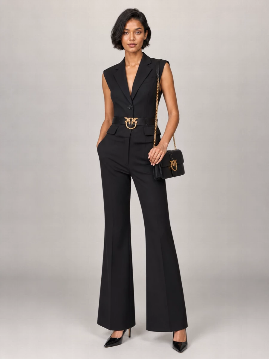 Sharp black flares meet a sleeveless tailored blazer for a clean, high-waisted column that feels confident and party-ready without losing polish. A signature bird-buckle belt and structured black shoulder bag in gold hardware add just enough shine, while sleek pointed pumps keep the line long and precise. The result is modern Italian suiting with a subtle Y2K attitude, perfect for evenings when you want tailoring to do the talking.