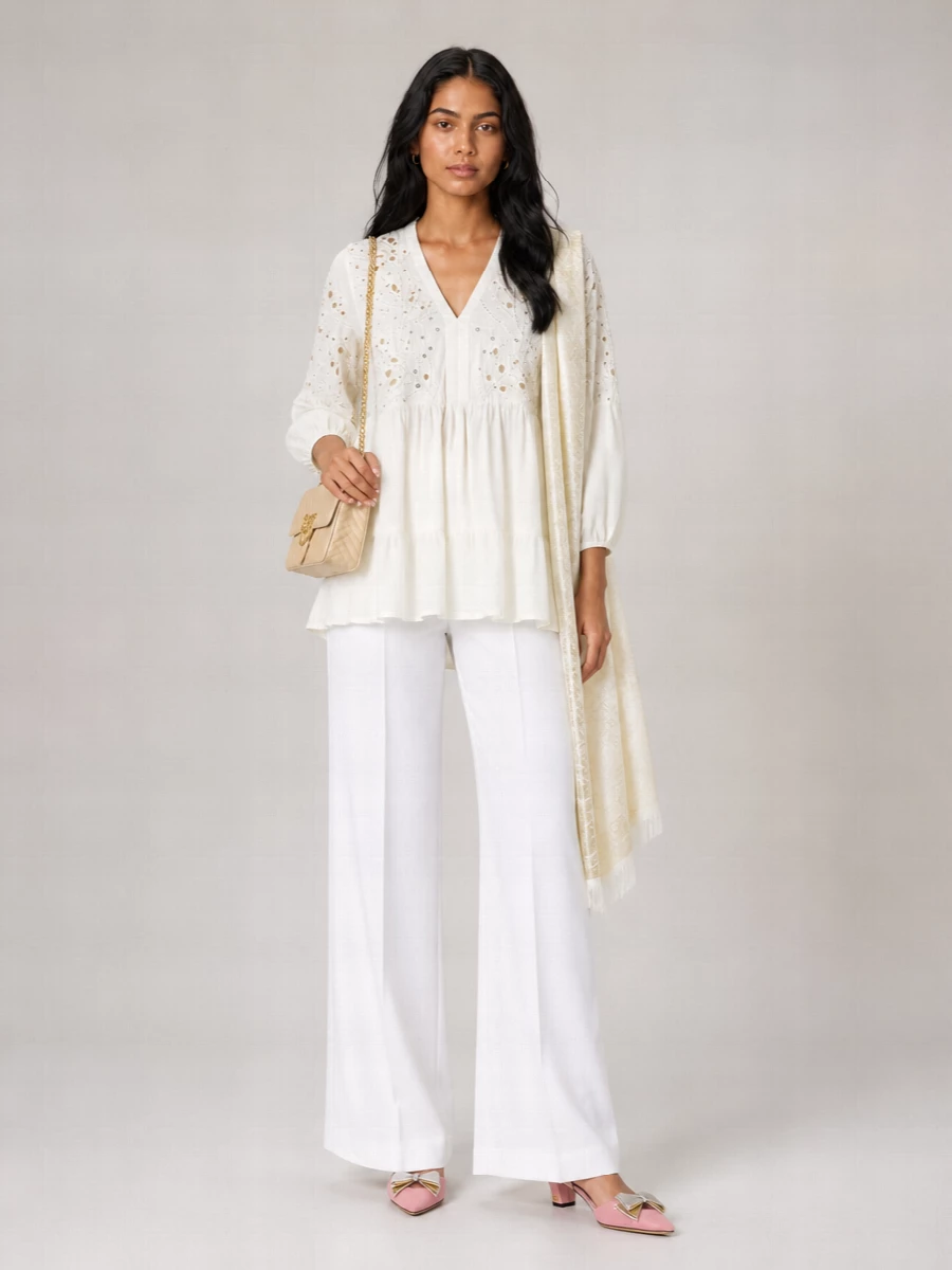 An ivory broderie tunic meets sharp white tailoring for a soft, elongated column that still feels relaxed. Blush-toned slingbacks and a cream Love Birds bag bring gentle romance without tipping into overt occasionwear. A tonal paisley stole finishes it with a barely-there boho nod that suits both city terraces and seaside dinners.