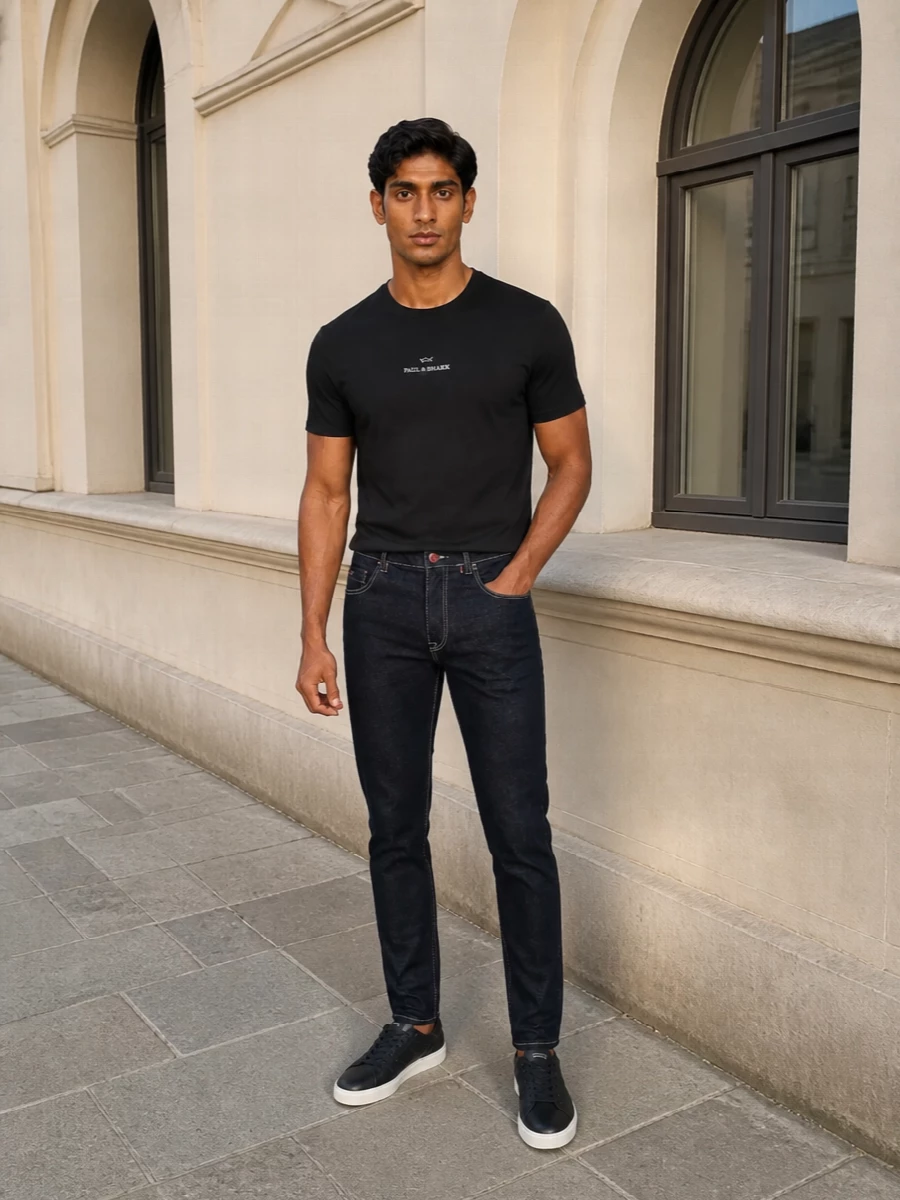 A black logo tee, dark indigo denim and navy leather sneakers create a clean, quietly athletic base that reads sharp without trying. The controlled monochrome and navy palette keeps everything aligned, from backpack to socks, for city days where you want polish and ease in equal measure. Subtle branding and neat proportions make this an easy uniform for travel, coffee runs or casual dinners.