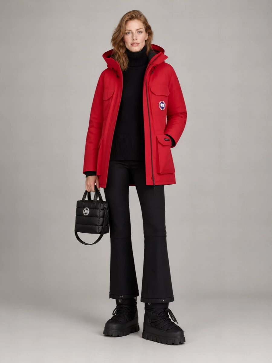 I am building around the parka as a true city-winter uniform, so I am choosing the top and bottom route rather than a dress, which would undermine the technical, utility mood and practical layering. The black Canada Goose knit and Moncler ski pant create a streamlined dark base that lets the red shell be the only loud note, while Prada snow boots and a quilted Moncler mini tote keep everything in a coherent performance-nylon world. It feels like polished alpine gear repurposed for brutal urban cold, with every piece earning its place functionally and aesthetically.