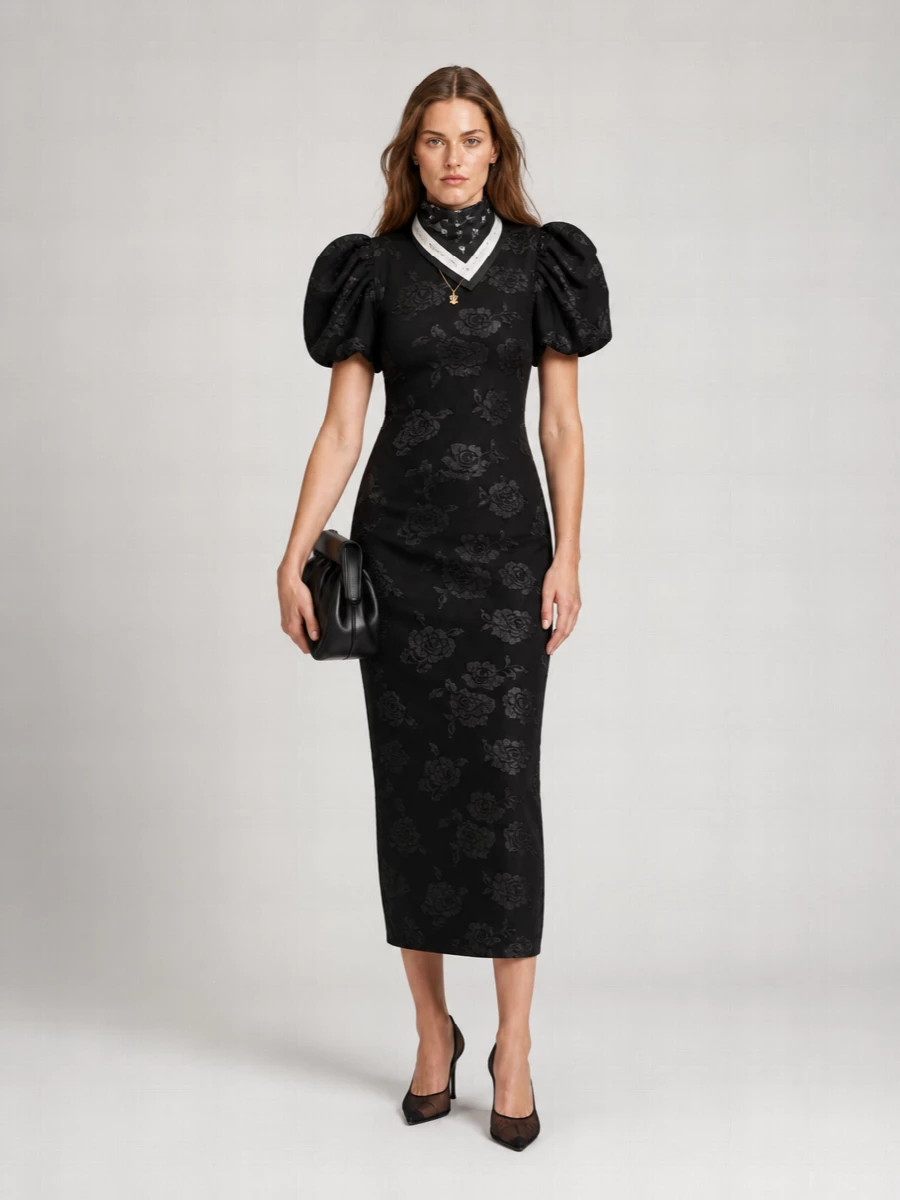 A dark, romantic column dress is sharpened with sheer black mesh stilettos and a sculptural black clutch for a quietly dramatic cocktail ensemble. The fine gold pendant adds a precise touch of light at the collarbone, while a monochrome silk scarf brings a modern graphic twist if you want a little extra styling detail. The result is polished, feminine and impactful without relying on overt embellishment.