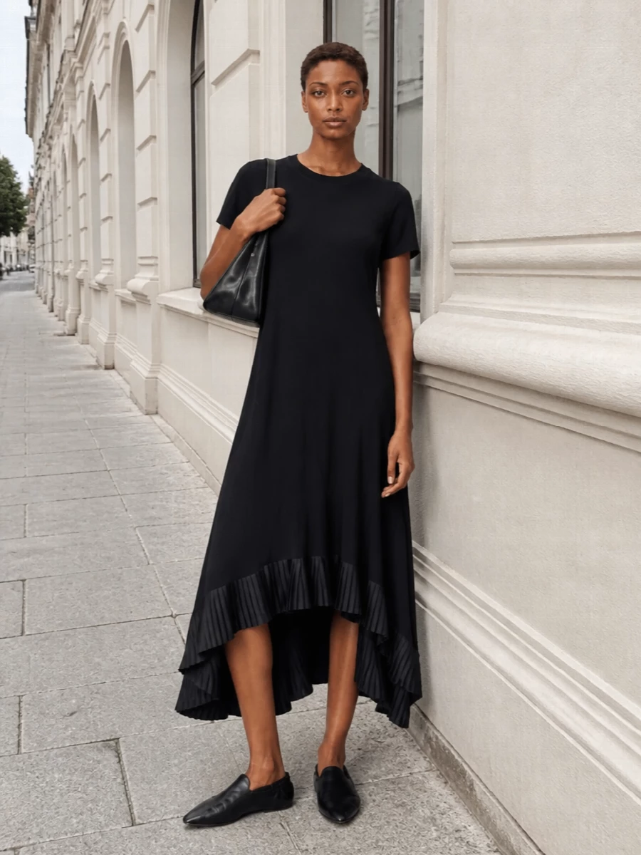 A Sacai asymmetric black midi dress pairs with The Row’s sculptural flats to echo the Acne shoulder bag’s clean, graphic line. The palette stays strictly monochrome, so the interest comes from proportion and movement rather than logos or hardware. This path leans into a single, confident dress silhouette instead of separates, keeping the story quietly modern and gallery-ready for warm days that slide into night.