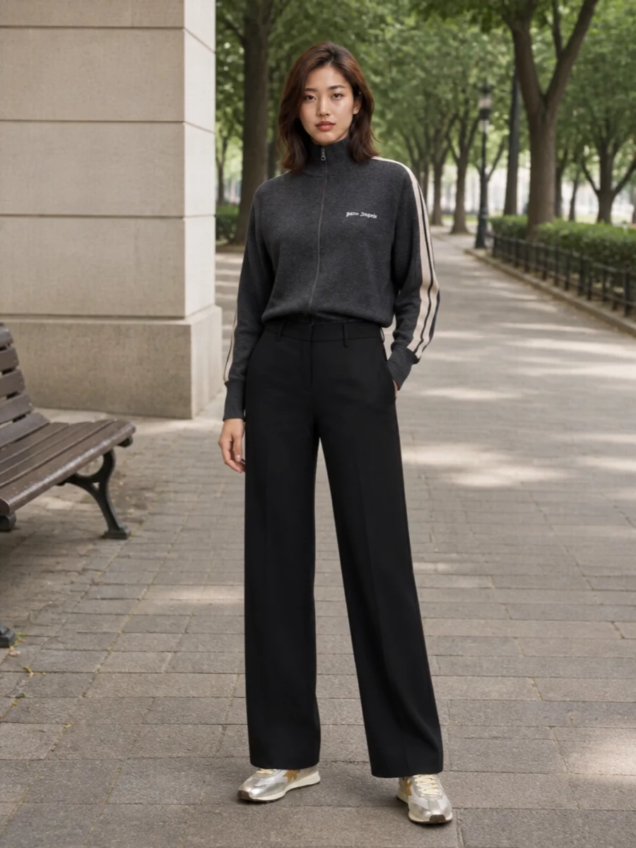 Charcoal track knit and matching wide-leg pants create a sleek, sport-informed base that lets the metallic runners stand out without feeling over-styled. The high waist and long, fluid leg balance the low-profile sneakers, while the pale structured bag adds a small hit of polish that still feels firmly streetwear. Together it reads like a modern city uniform, relaxed enough for day but sharp in proportion and detail.