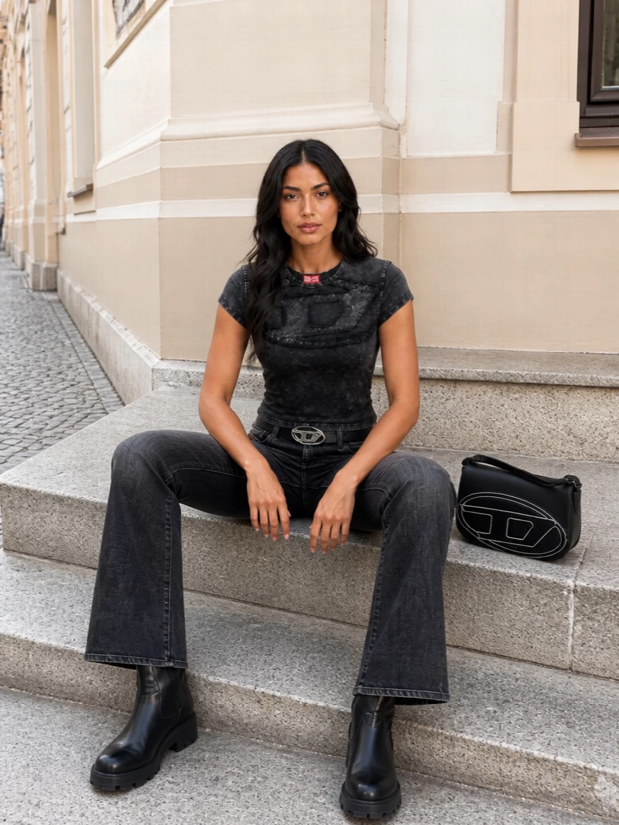 A washed-black flare and sculpted Diesel tee create a lean, grungy Y2K take on head-to-toe charcoal. Chunky logo boots and a structured logo shoulder bag double down on the industrial attitude, while a slim D-buckle belt sharpens the waist so the proportions stay long and clean.