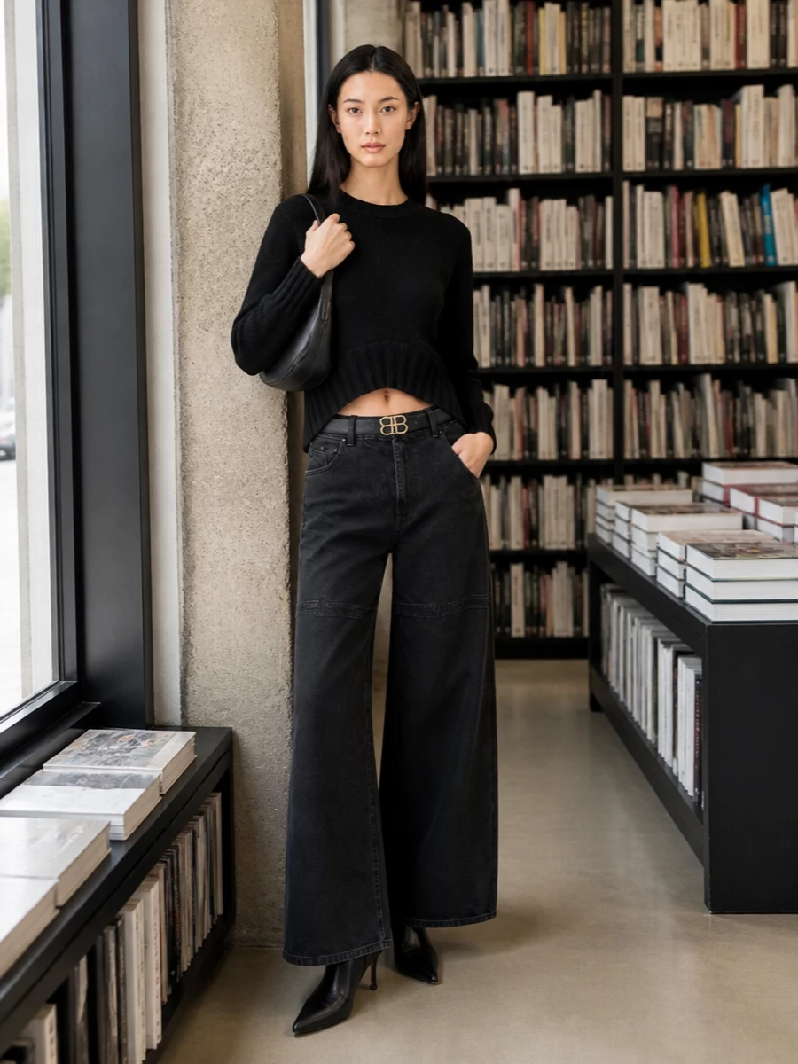Washed black wide-leg denim meets a sculpted Attico knit for a clean, directional base in deep charcoal and black. A sharp Balenciaga ankle boot extends the line and keeps the silhouette lean under the volume of the jean. A triangular Attico shoulder bag and a slim Balenciaga belt finish it with precise, architectural details that feel right for city days that run late.