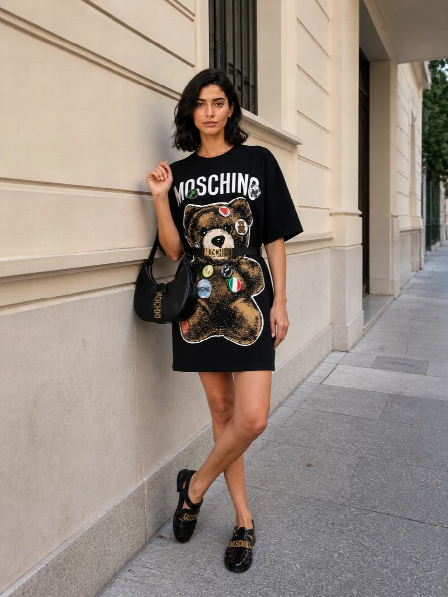 Moschino’s teddy tee dress stays pure street, toughened up with glossy black jelly sandals and a curved logo hobo. The black and gold story keeps it tight and graphic. Cinch the waist with the slim logo belt when you want a sharper, more defined shape.