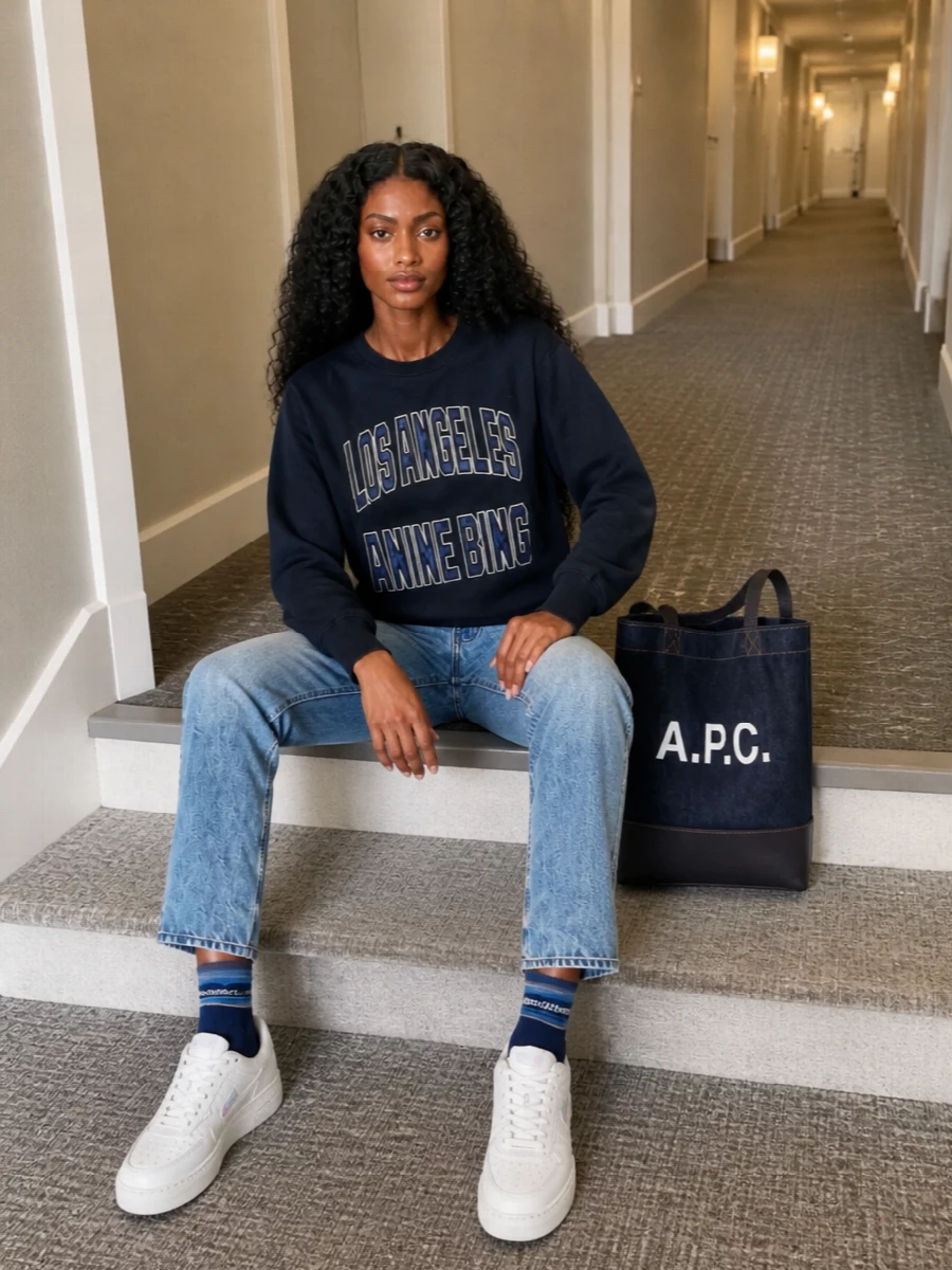 Ink navy collegiate energy, washed light denim and crisp white sneakers keep this Anine Bing sweatshirt firmly in its LA off duty lane. The straight leg balances the easy top, while the navy tote and striped socks pull the palette together so it feels sporty but grown up, not teenage. It is the kind of uniform that works from coffee runs to casual Fridays with zero effort required from you once it is in your wardrobe.