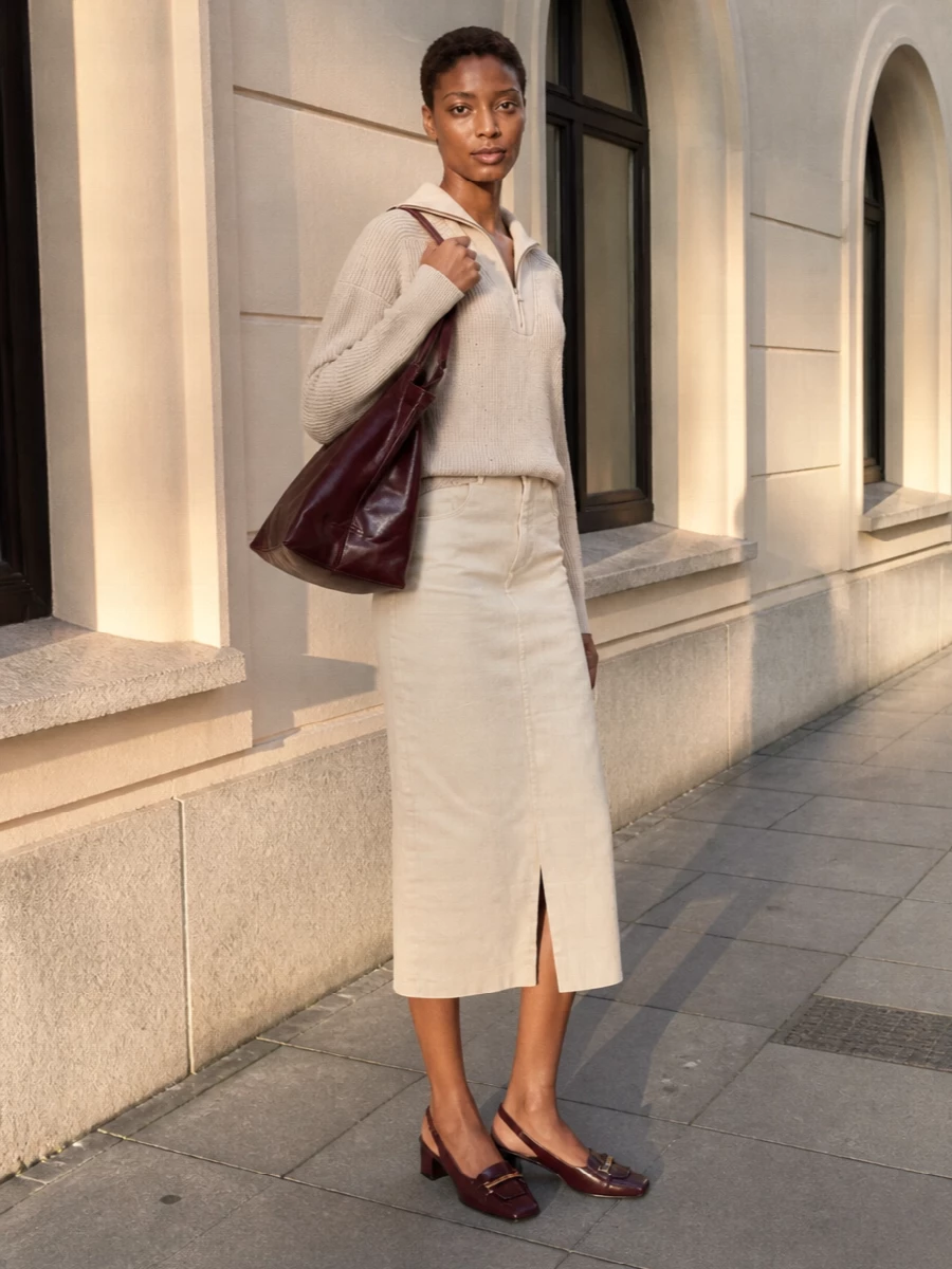 I’m taking the top and skirt route here to keep things relaxed but put-together around the structured burgundy tote. The oatmeal half‑zip and cream midi skirt create a soft, tonal column that feels calm, while the burgundy slingback repeats the bag’s colour so the accessories read intentional rather than shouty. It’s an easy city uniform for cooler months, quietly polished but still comfortable enough to live in all day.