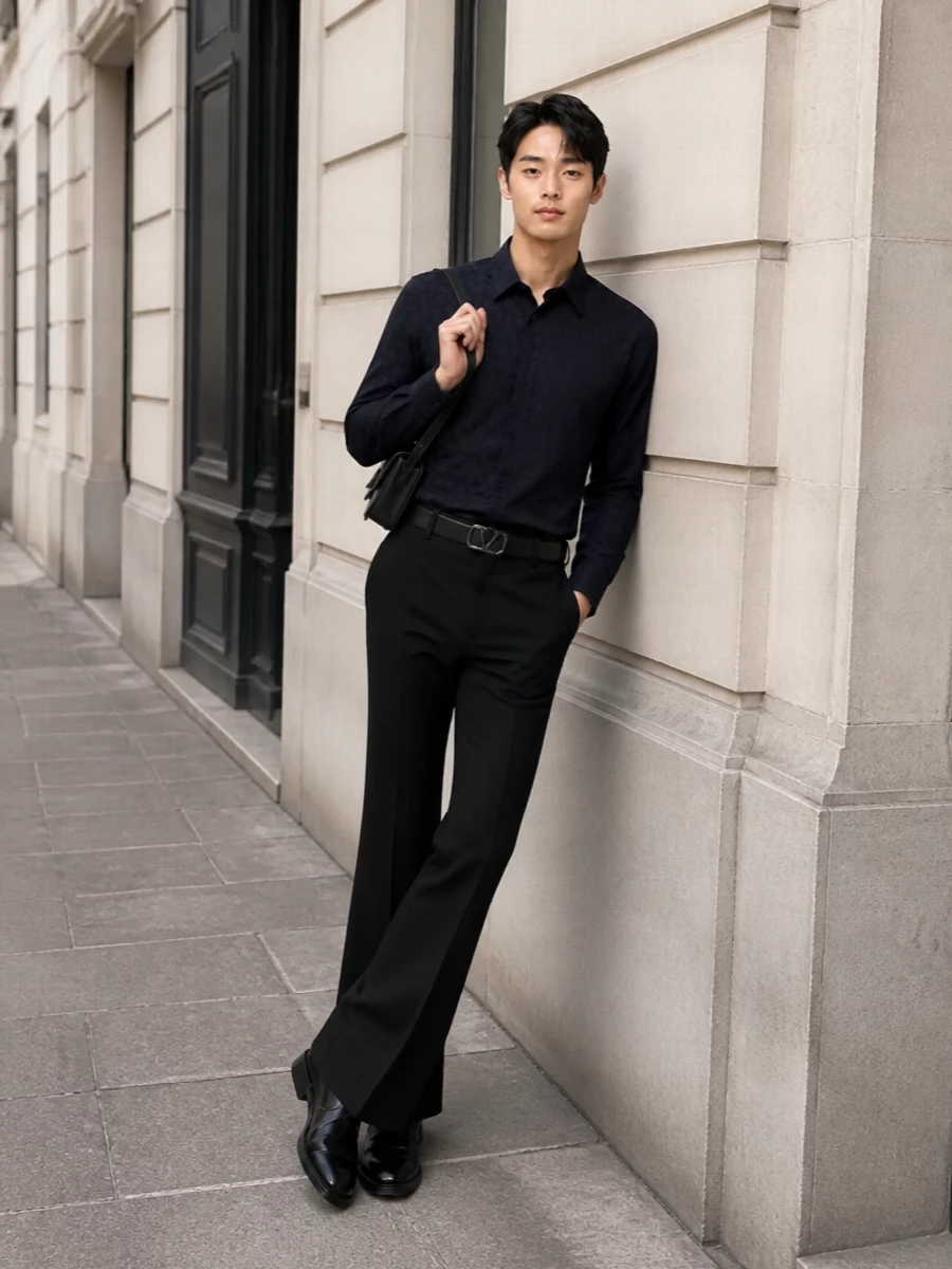 This look builds a dark, elongated evening silhouette around the sharply flared Valentino trouser, paired with an inky jacquard shirt that adds depth without disturbing the minimalist line. Clean black derbies, a slim structured black shoulder bag, and a discreet logo belt keep the profile razor sharp and couture-inflected, ideal for formal dinners or gallery openings where quiet luxury needs presence rather than flash.
