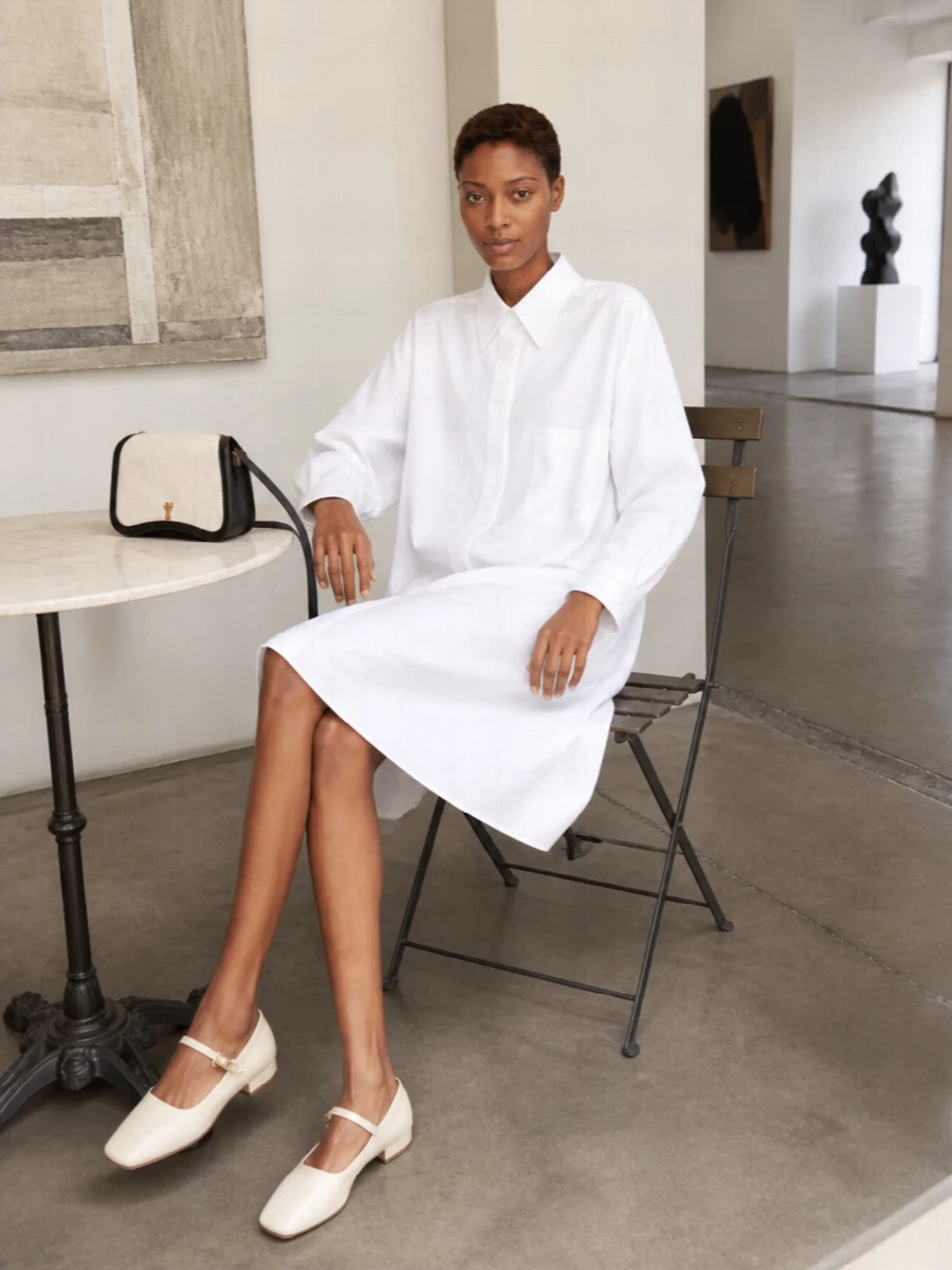 A crisp white Bottega shirt dress paired with the cream-and-black Ami bag creates a quietly assertive, gallery-ready uniform. Cream square-toe ballerinas keep the line relaxed yet polished, letting the sharp monochrome palette do the work. Choosing the dress route instead of top-and-trouser tailoring keeps the silhouette unfussy and heightens that Paris-meets-Milan ease the bag already suggests.