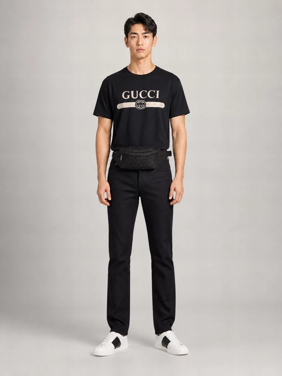 A black Gucci logo tee is grounded by inky Armani denim for a clean, monochrome base that feels street-led but quietly polished. Valentino’s graphic low-tops echo the tee’s contrast logo, while the quilted belt bag keeps essentials close and the silhouette neat. It is an easy city uniform that leans preppy through its structure and restrained palette rather than loud branding.